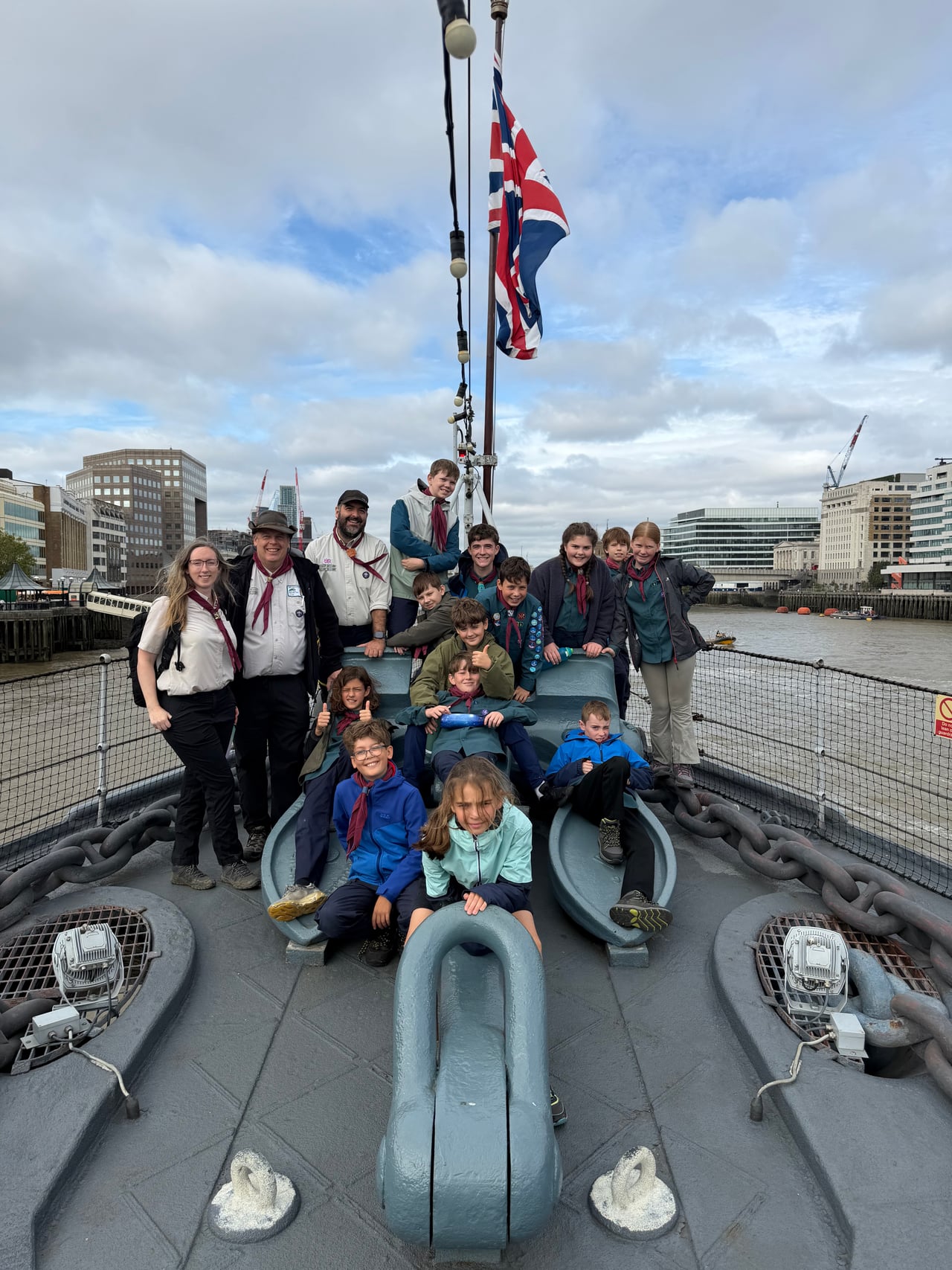 Scouts and leaders posing together on the deck of HMS Belfast